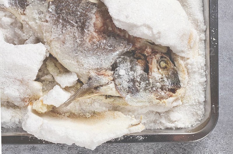 Baked Dorado fish, in salt on a baking sheet, top view, homemade, no people