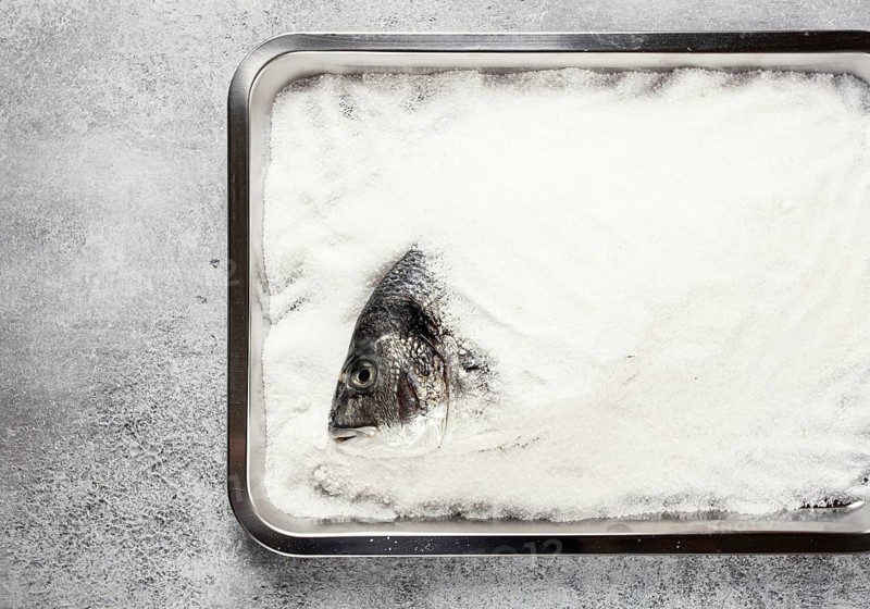 Fresh Dorado fish, cooked in coarse salt, on a tray, top view, close-up, no people