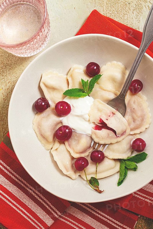 Traditional dumplings with cherries and yogurt, close-up, no people
