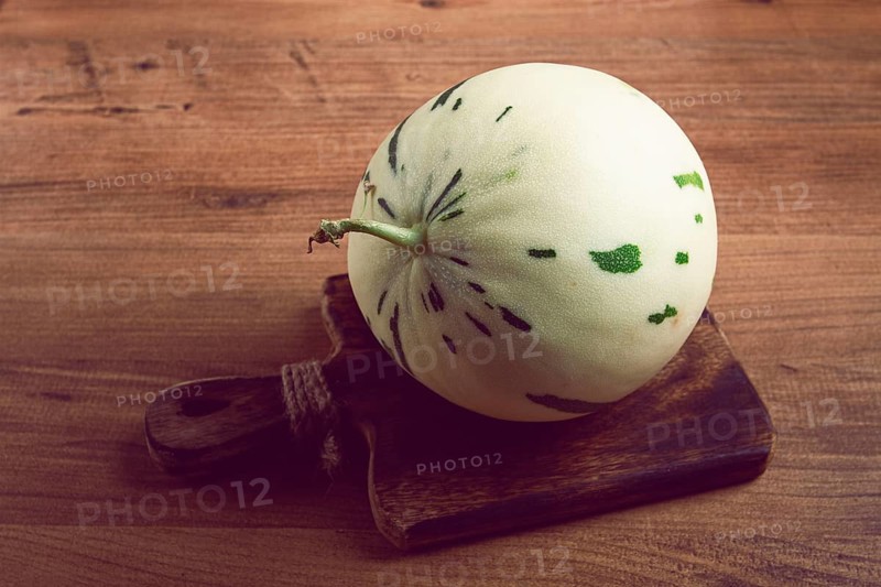Dino melon, white with green stripes, small size, on the table, close-up, no people