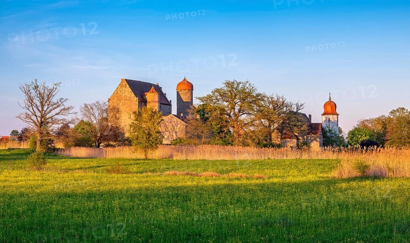 View over wildflower meadow at Sommersdorf Castle near Burgoberbach in the AltmÃ¼hl Valley in the evening light, Middle Franconia, Bavaria, Germany