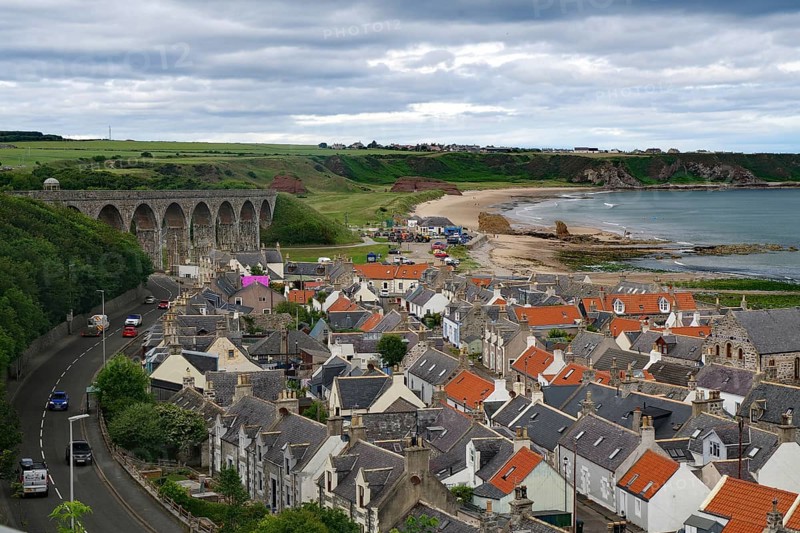 Coastal town with a viaduct and orange tiled roofs under a cloudy sky, Portsoy, Aberdeenshire, Scotland, United Kingdom