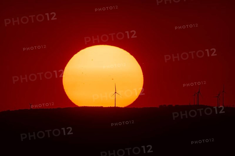 From the summit plateau of the GroÃŸer Feldberg in the Taunus mountains, you can watch the sun set behind several wind turbines on the distant horizon, Hesse, Germany