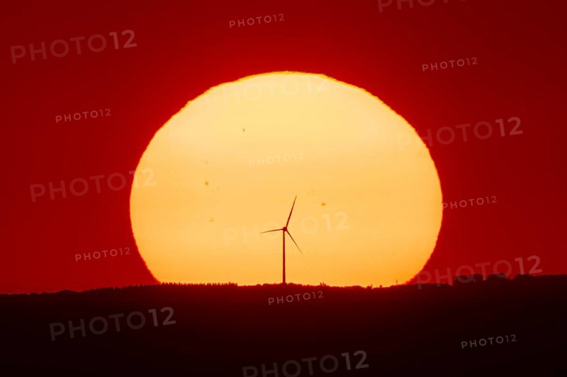 From the summit plateau of the GroÃŸer Feldberg in the Taunus mountains, you can watch the sun set behind a wind turbine on the distant horizon, Hesse, Germany
