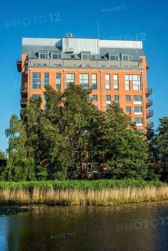 Newly (2025) built apartment building rising above the trees and behind a pond in Ystad, SkÃ¥ne County, Sweden, Scandinavia