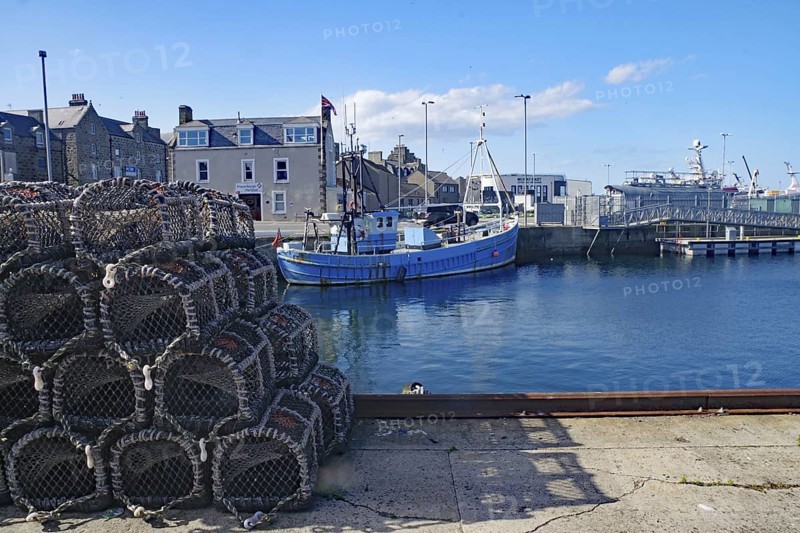 A harbour with fishing boats and stacked nets under a clear sky, Fraserburgh Aberdeenshire, Scotland, United Kingdom