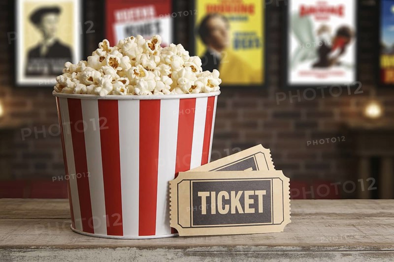 Red and white striped popcorn bucket with vintage movie tickets on wooden surface. Generative ai, AI generated