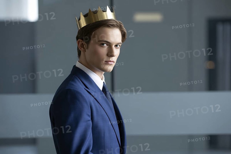 Young man in suit wearing golden crown. Studio portrait symbolizes quiet male authority and the persistence of patriarchal ideals. Generative Ai, AI generated