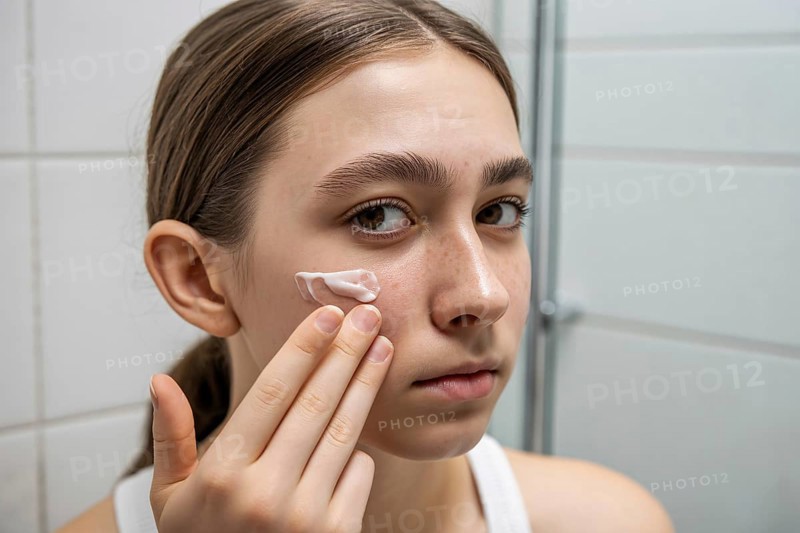 Teenager applying skin cream in bathroom. Honest daily skincare and self-care routine. Generative ai, AI generated