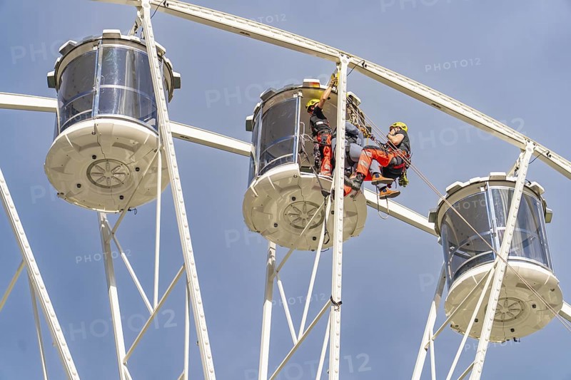 Two workers in equipment working on the structure of a Ferris wheel, fire brigade exercise for gondola rescue, Germany
