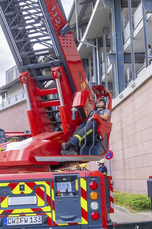 Firefighter resting on an extended lifting platform next to a building, fire brigade exercise for gondola rescue, Germany