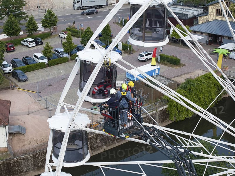 Firefighters during a rescue exercise on a Ferris wheel in an urban environment with parked cars, fire brigade exercise for gondola rescue, Germany