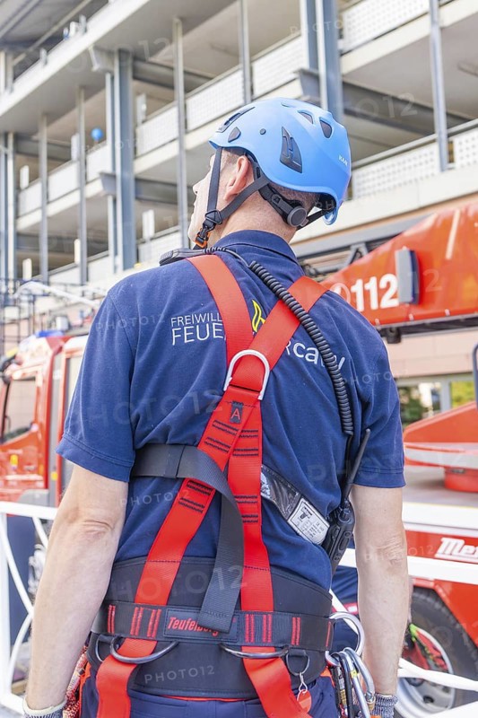 Fire brigade employee with safety equipment looking at a vehicle, fire brigade exercise for gondola rescue, Germany