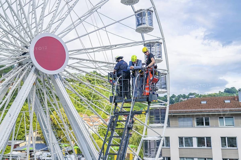Firefighters carry out rescue operation on a Ferris wheel in a city, fire brigade exercise for gondola rescue, Germany