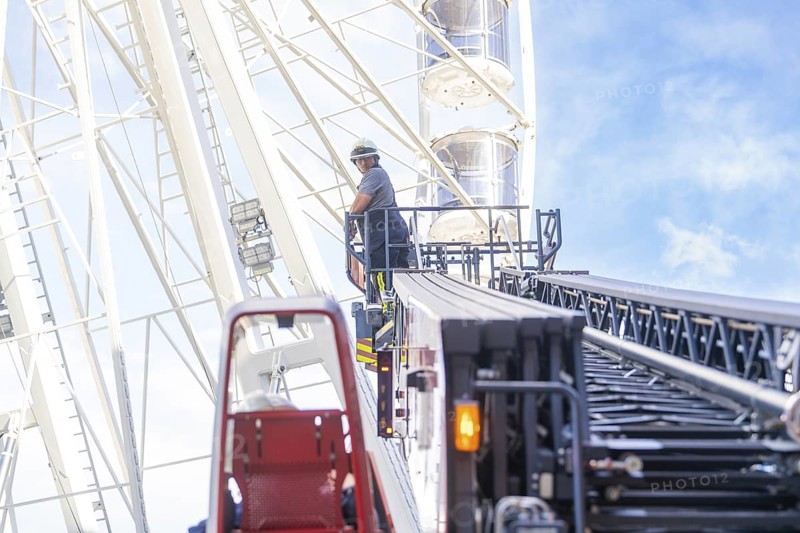 Firefighter on a lifting platform next to a Ferris wheel in front of a clear sky, fire brigade exercise for gondola rescue Ferris wheel, Calw, Germany