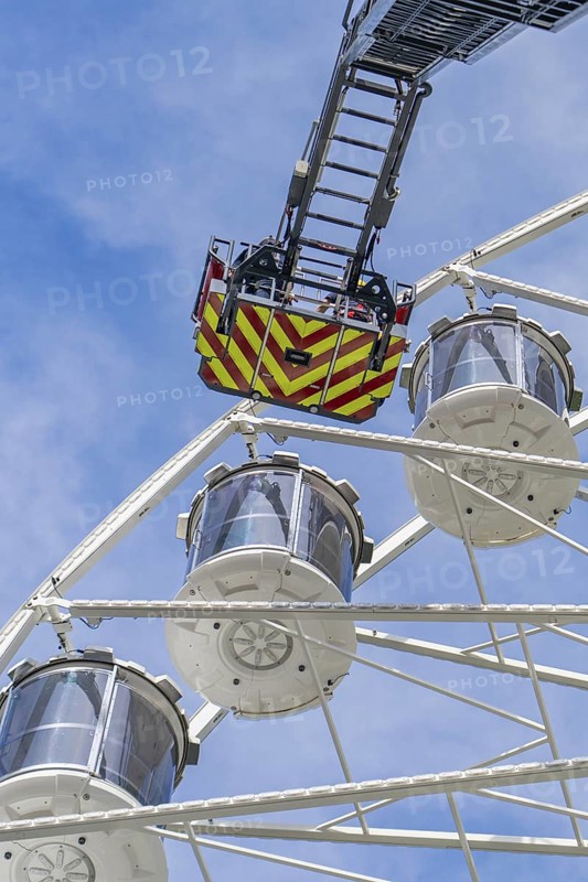Rescue ladder of the fire engine reaches the cabins of the Ferris wheel, background with blue sky, fire brigade exercise for gondola rescue Ferris wheel, Calw, Germany
