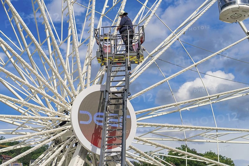 A worker on a ladder, the Ferris wheel and the blue sky characterise the scene, Fire brigade exercise for gondola rescue Ferris wheel, Calw, Germany