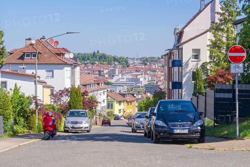 Urban street with cars, a no cycling sign, a scooter and a backdrop of houses under a clear sky, Pforzheim, Germany