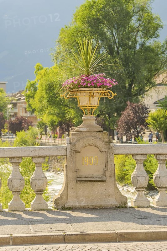 Stone bridge with decorative flower pot, inscription 1909, sunny day, Merano, South Tyrol, Italy