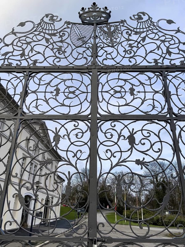 Wrought-iron Tor tor with ornaments and forged tendrils and stylised crown between Sclossgarten and former castle courtyard of Borbeck Castle historic summer residence of prince abbesses of Damenstift, Essen, North Rhine-Westphalia, Germany