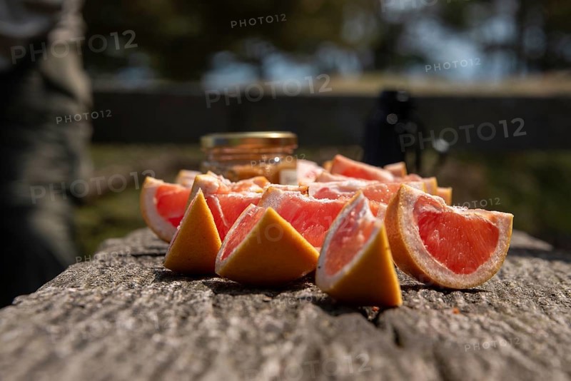 Sliced grapefruits on a wooden table in the sun with a blurred background, Prerow, Mecklenburg-Vorpommern, Germany