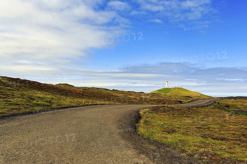 Winding tarmac road leads through barren volcanic landscape, Reykjanesviti lighthouse on the horizon, Reykjanes peninsula, near Reykjavik, Iceland