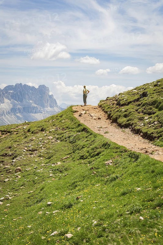 Hikers on a path in a mountainous landscape under a blue sky, Schlehrn hike, Alpe di Siusi, Dolomites, South Tyrol, Italy