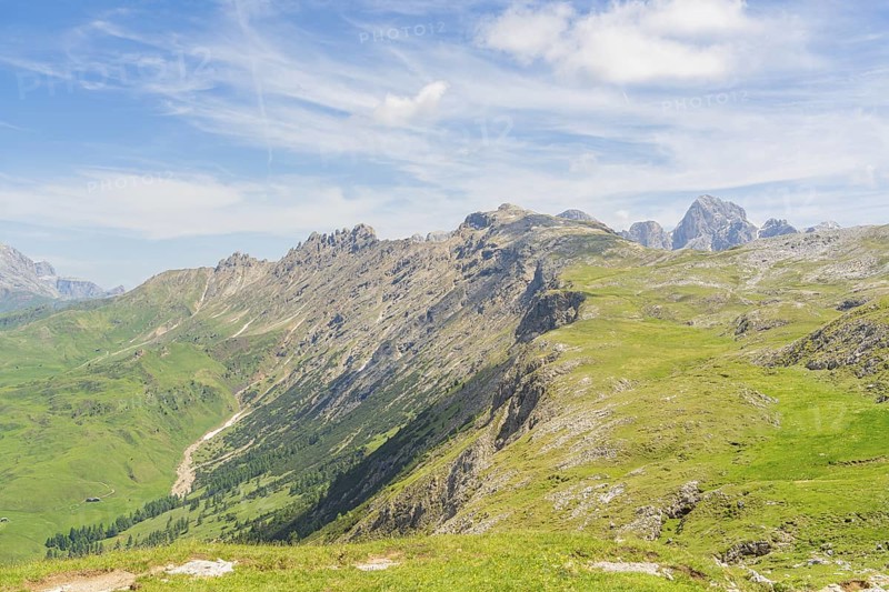 Extensive mountain landscape with green hills and blue sky in the background, Schlehrn hike, Alpe di Siusi, Dolomites, South Tyrol, Italy