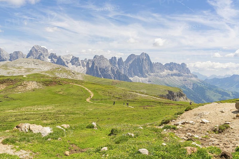 Panorama of a mountain path in the middle of a vast mountain landscape under a blue sky, Schlehrn hike, Alpe di Siusi, Dolomites, South Tyrol, Italy
