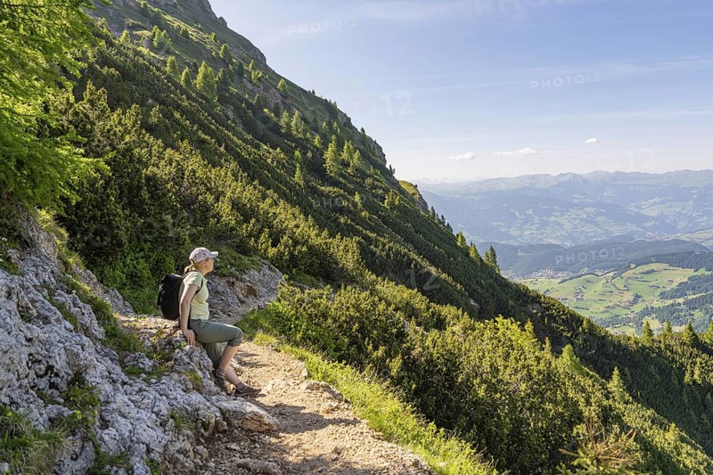 Hiker sitting on a mountain path with a view of the valley, hike to the Schlehrn, Alpe di Siusi, Dolomites, South Tyrol, Italy