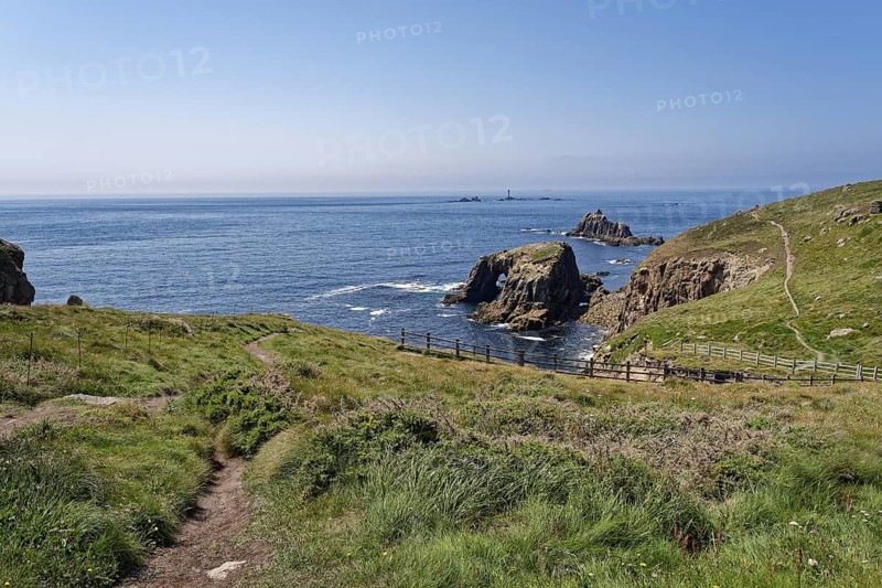 View from Land's End of the coastal footpath and the lighthouse off the coast. Land's End, the tip of the headland in the west of Cornwall, is the most westerly point in England. Land's End, Sennen, Penzance, Cornwall, South West England, Great Britain