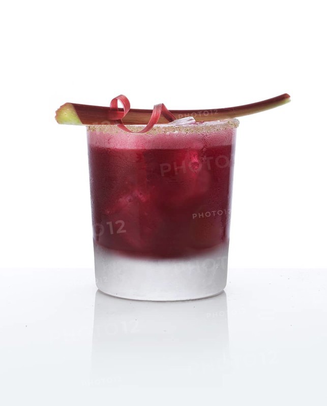 Cocktail in a tumbler on ice with rhubarb stalk as garnish against a white background, studio shot