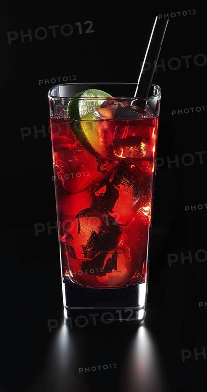 Cocktail in a long drink glass on ice with a slice of lime and as a garnish in front of a black background, studio shot