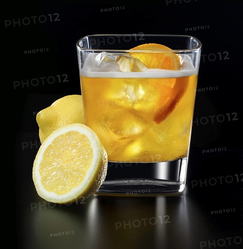 Cocktail in a tumbler on ice with orange slice and lemons as garnish against a black background, studio shot