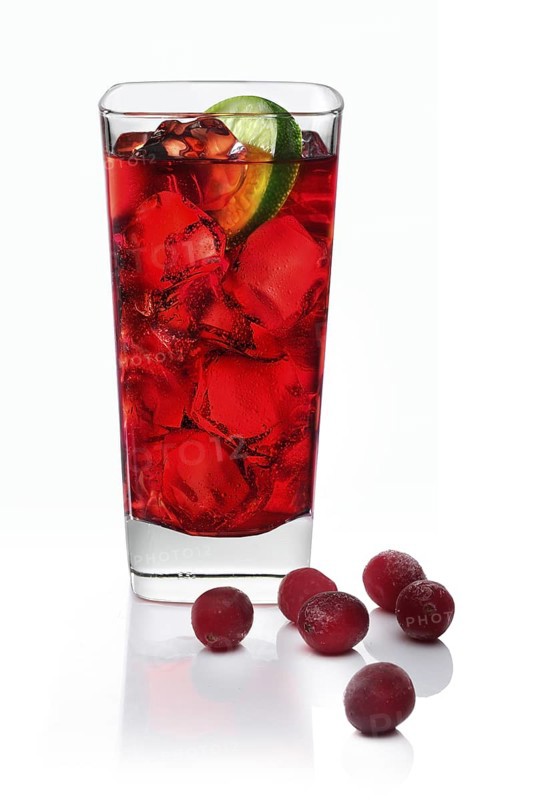 Cocktail in a long drink glass on ice with a slice of lime and cranberries as garnish against a white background, studio shot
