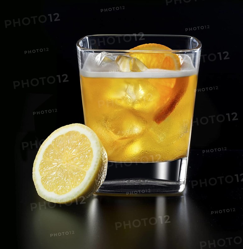 Cocktail in a tumbler on ice with half a slice of orange and half a lemon as garnish against a black background, studio shot