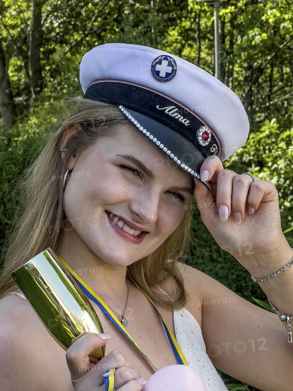 Happy blonde student on graduation day, holding her cap and smiling at the camera, in Ystad, SkÃ¥ne County, Sweden, Scandinavia
