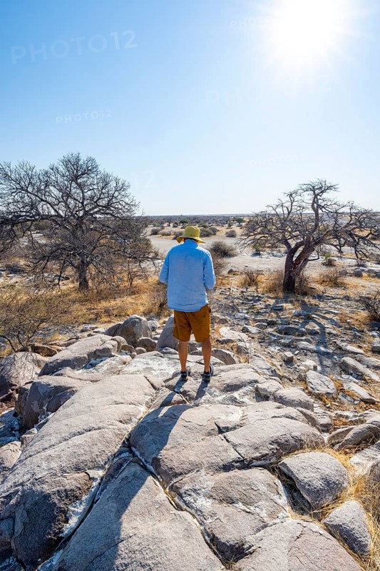 Tourist on a hill with baobabs, African baobab or monkey bread tree (Adansonia digitata), view over Kubu Island (Lekubu), Sowa Pan, Makgadikgadi salt pans, Botswana