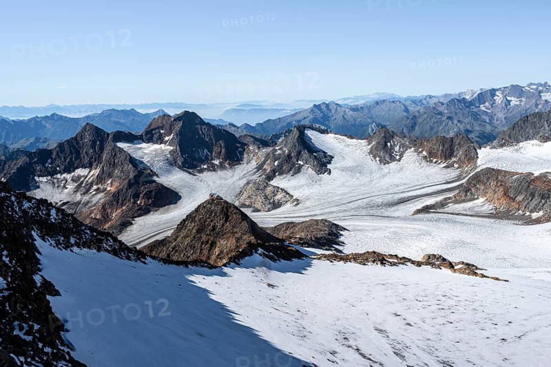 Narrow rocky ridge at the Wilder Freiger summit, picturesque high mountain landscape with snow, view of Ãœbeltalferner glacier and rocky mountain peaks Königshofspitz and Sonklarspitze, Stubai Alps, South Tyrol, Italy