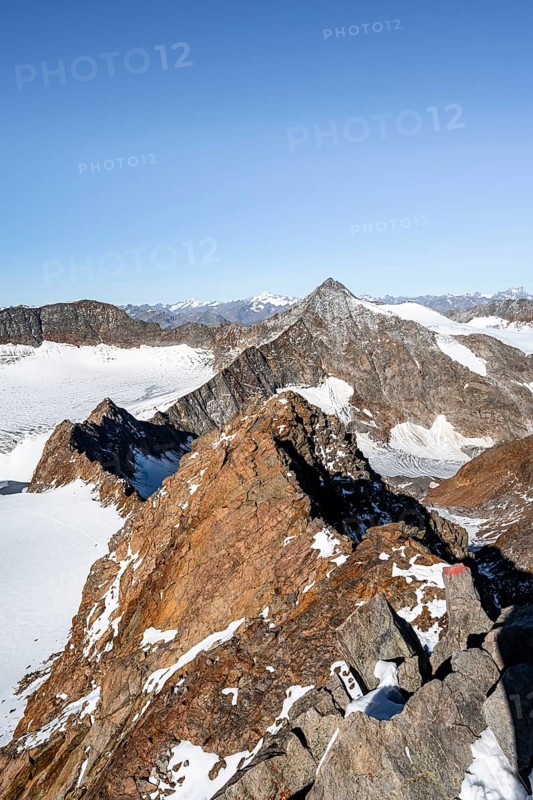 Narrow rocky ridge on the Wilder Freiger summit, picturesque high mountain landscape with snow, view of Ãœbeltalferner glacier and rocky Wilder Pfaff mountain summit, Stubai Alps, South Tyrol, Italy