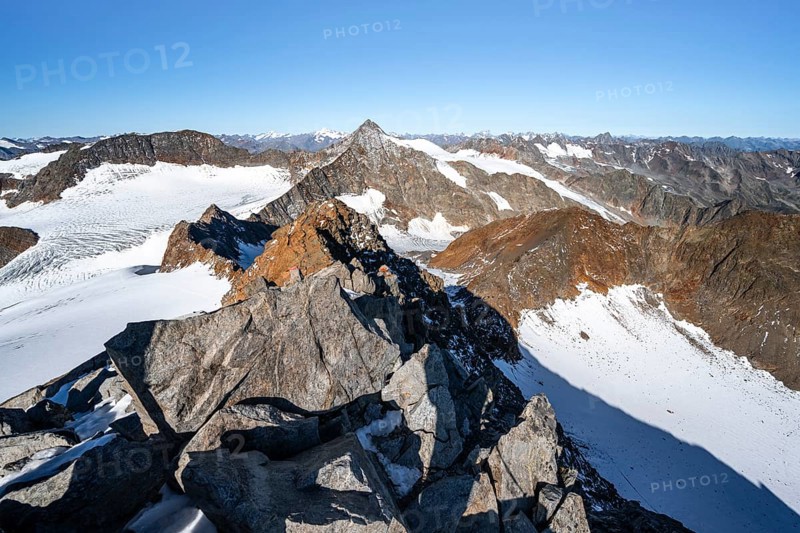 Narrow rocky ridge on the Wilder Freiger summit, picturesque high mountain landscape with snow, view of Ãœbeltalferner glacier and rocky Wilder Pfaff mountain summit, Stubai Alps, South Tyrol, Italy