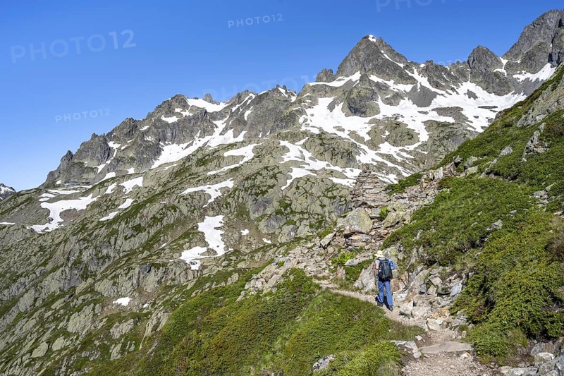 Mountaineer on hiking trail, summit of the Aiguilles rouges with snow remains, Chamonix, Haute-Savoie, France