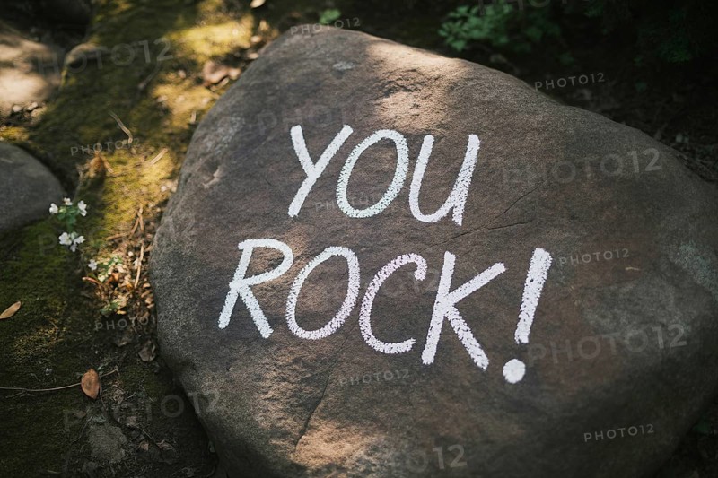 Top view close-up of a rough grey rock in a forest setting, featuring You rock! handwritten in white chalk. Natural surroundings with moss and leaves create an encouraging, uplifting atmosphere Generative Ai, AI generated