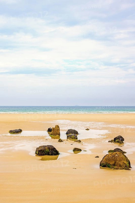 Rocks on a empty sand beach with a sea view towards the horizon in the summer, Crozon Peninsula, Bretagne, France