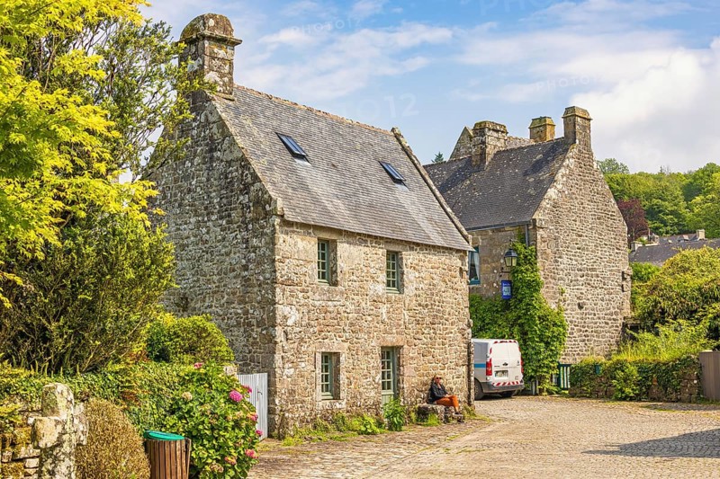 Idyllic old french village with stone houses and cobblestone streets and lush green trees a sunny summer day, Locronan, Crozon Peninsula, Bretagne, France