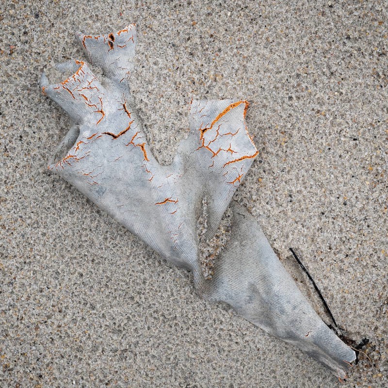 Old plastic glove in the sand with visible cracks, symbolising pollution and human waste, beach, RingkÃ¸bing Fjord, Jutland, Denmark