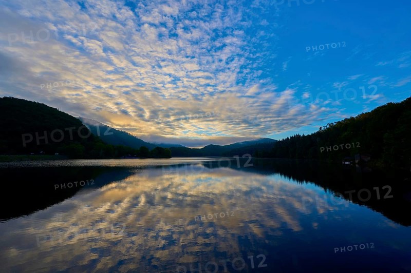 Peaceful morning atmosphere with dramatic sky reflected on the still lake, surrounded by green mountains, summer, Rursee, Obersee, Rurberg, Simmerath, Eifel National Park, Eifel, North Rhine-Westphalia, Germany