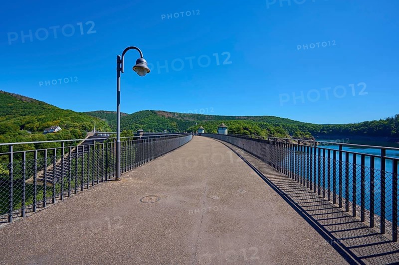 Asphalted bridge with railing over a water reservoir under a blue sky, summer, Urft dam, Obersee, Urftsee, Schleiden, Eifel National Park, Eifel, North Rhine-Westphalia, Germany