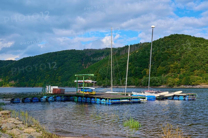 Jetty with boats in front of wooded hills and clouds, summer, Rursee, Rurberg, Simmerath, Eifel National Park, North Rhine-Westphalia, Germany