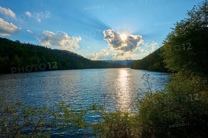 Sunset over a lake with wooded hills, clear reflection on the water surface, summer, Rursee, Obersee, Simmerath, Eifel National Park, North Rhine-Westphalia, Germany